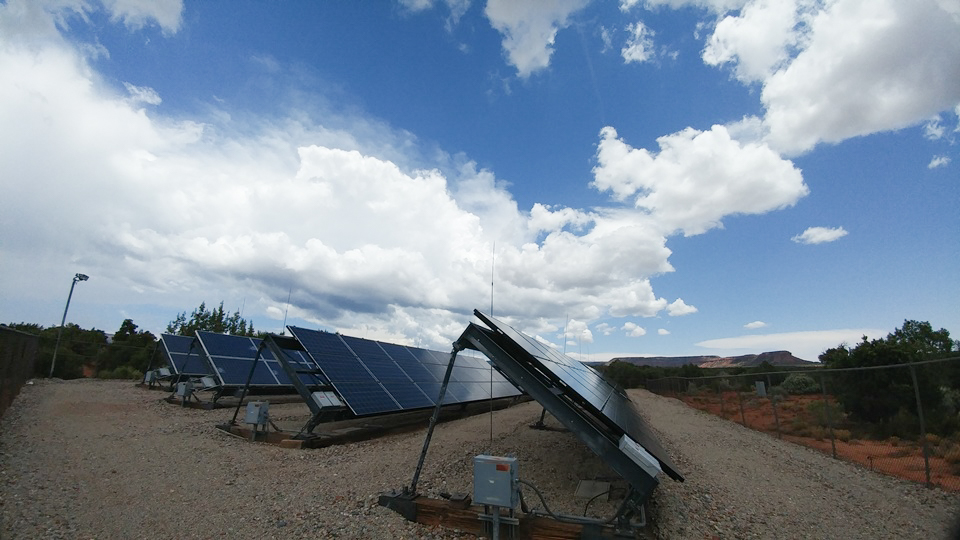 a group of solar panels under a partly cloudy sky