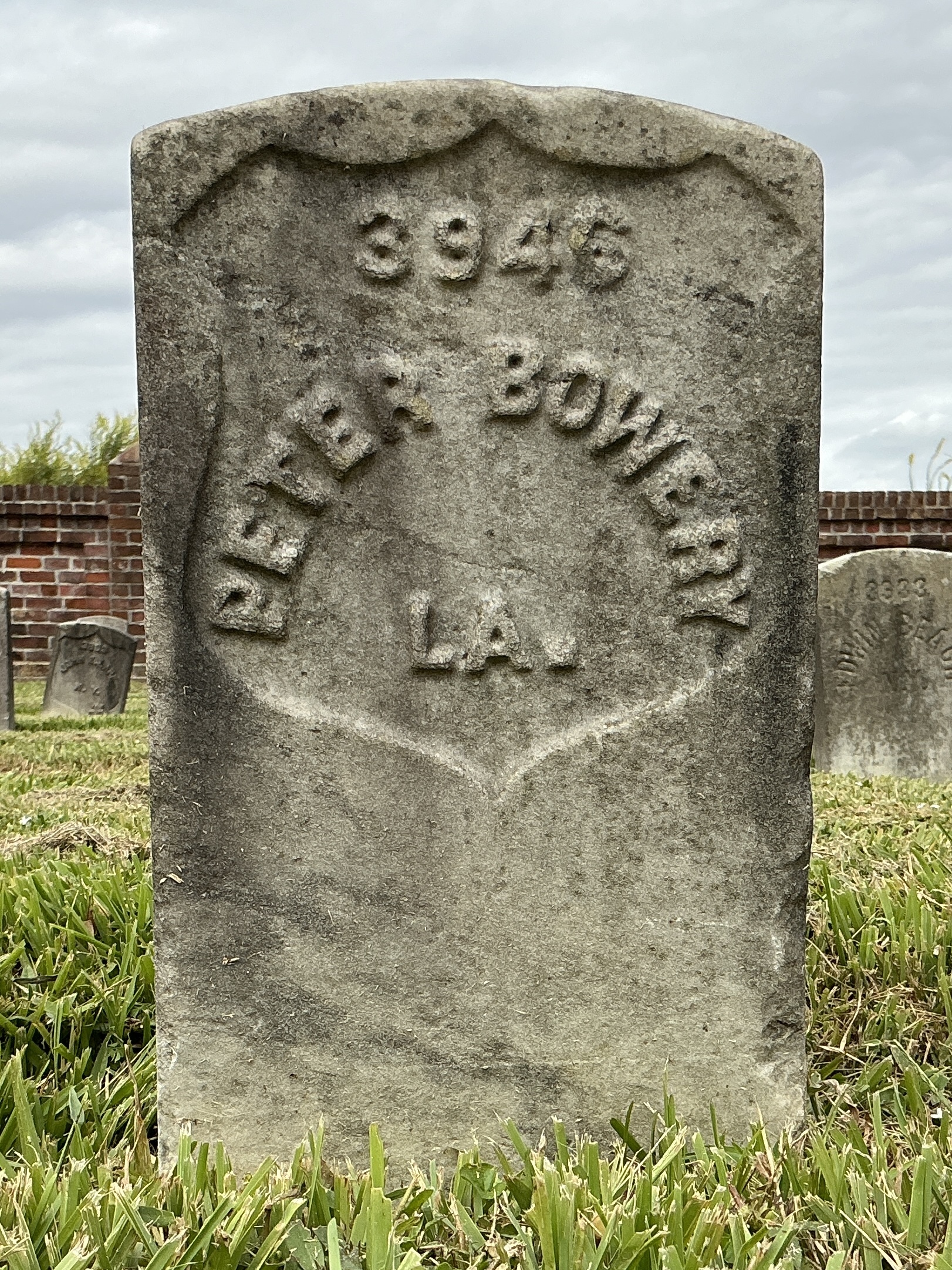Front of historic upright marble headstone with recessed shield face.