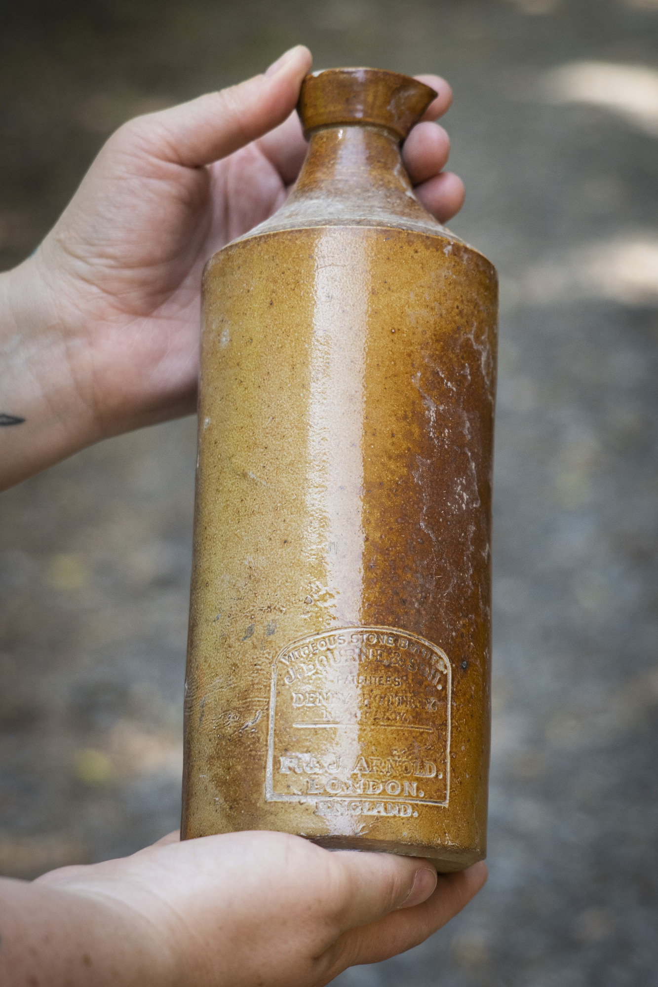 A brown stoneware bottle stamped with a brand logo.