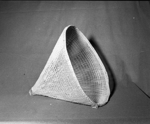 Mrs. Donald Segerstrom Collection. Object: Miwok burden basket. Dimensions: 21 x 22". Materials: Peeled shoots, split Ceanothus sp., commercial shoe leather sewn on with cotton string. Technology: Diagonally twined, up to right slant of turns, splice overlapped by four or five turns of twining, warp rods bent to left and bound, rimstick sewn on top (prob. Ceanothus sp.). Collection History: Carrie Segerstrom tag attached reads "This acorn basket I purchased at Cherokee 36 years ago." Tag written before 1946. Photographed by Michael Dixon. Catalogued by Craig Bates and Barbara Beroza. Yosemite Collections, National Park Service. 1/83.