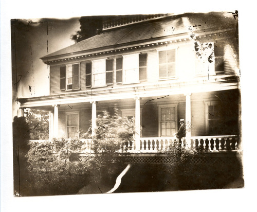 Black and white photograph of man on porch.