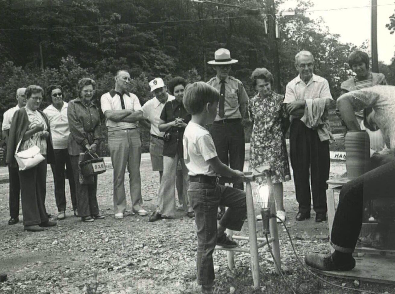 Man shows a group of people how to throw pottery on a wheel