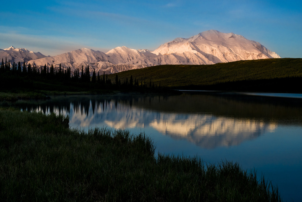 A landscape of hills, forests and a huge, snowy mountain
