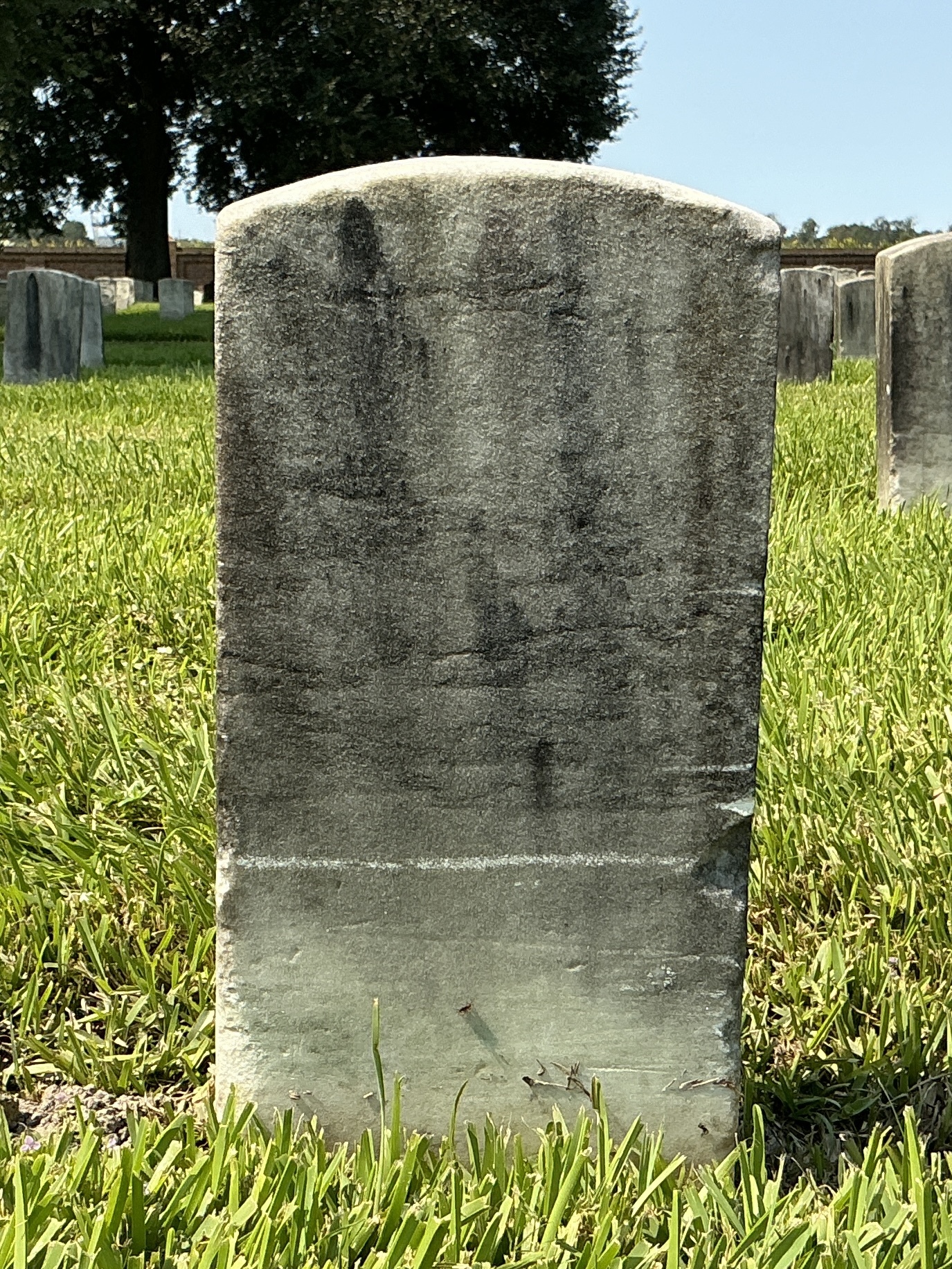 Back of historic upright marble headstone with recessed shield face.