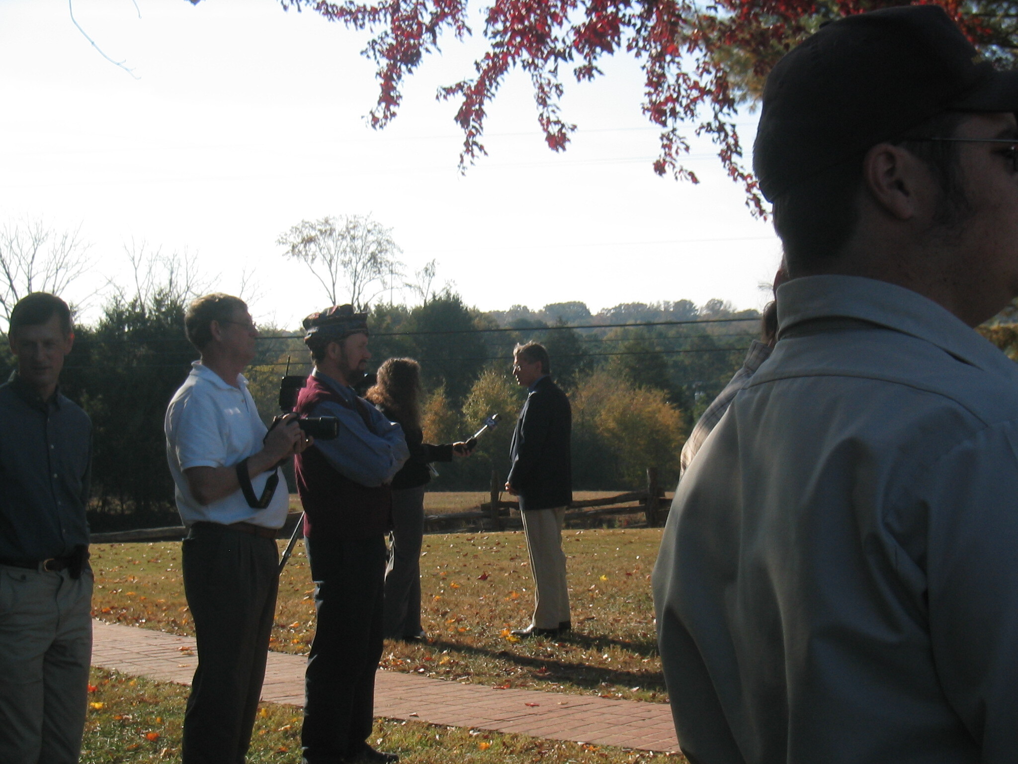 A group of people standing in a grassland with trees in the background.