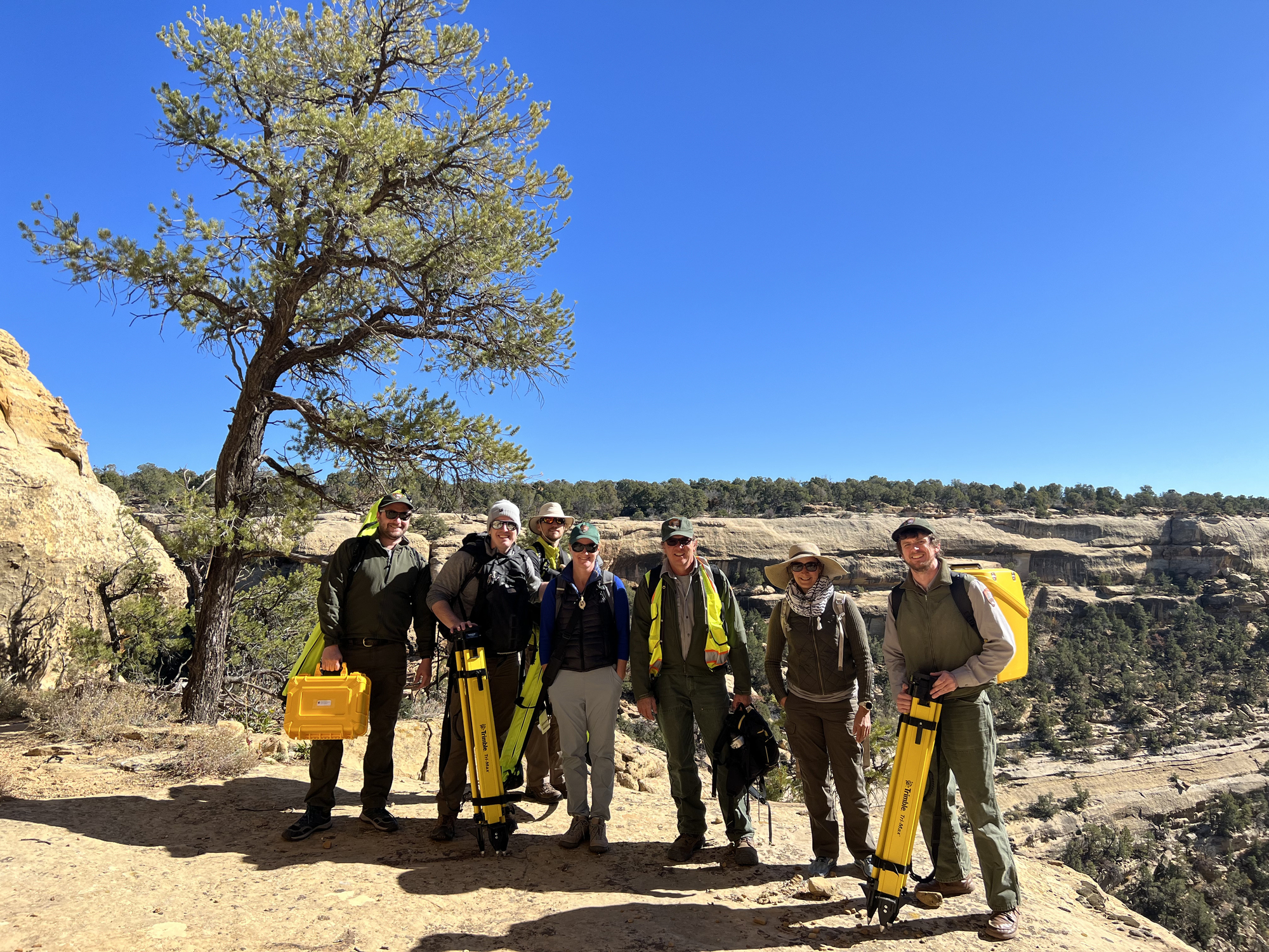 NPS personel carrying survey equipment into canyon at Mesa Verde National Park.