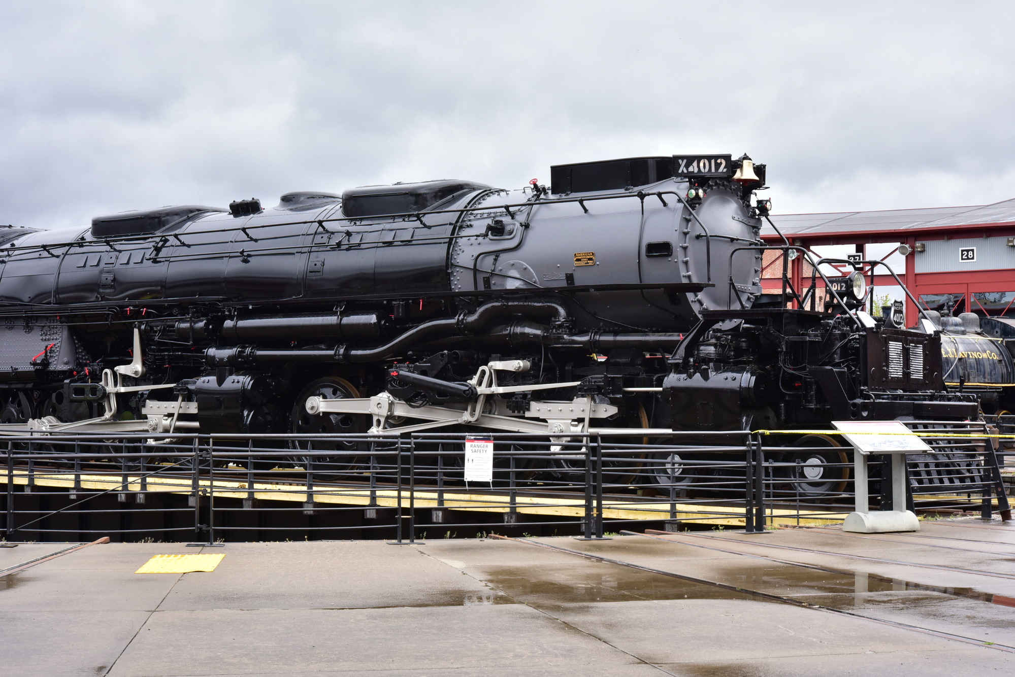Ground level view of large black train on roundtable track behind a railing