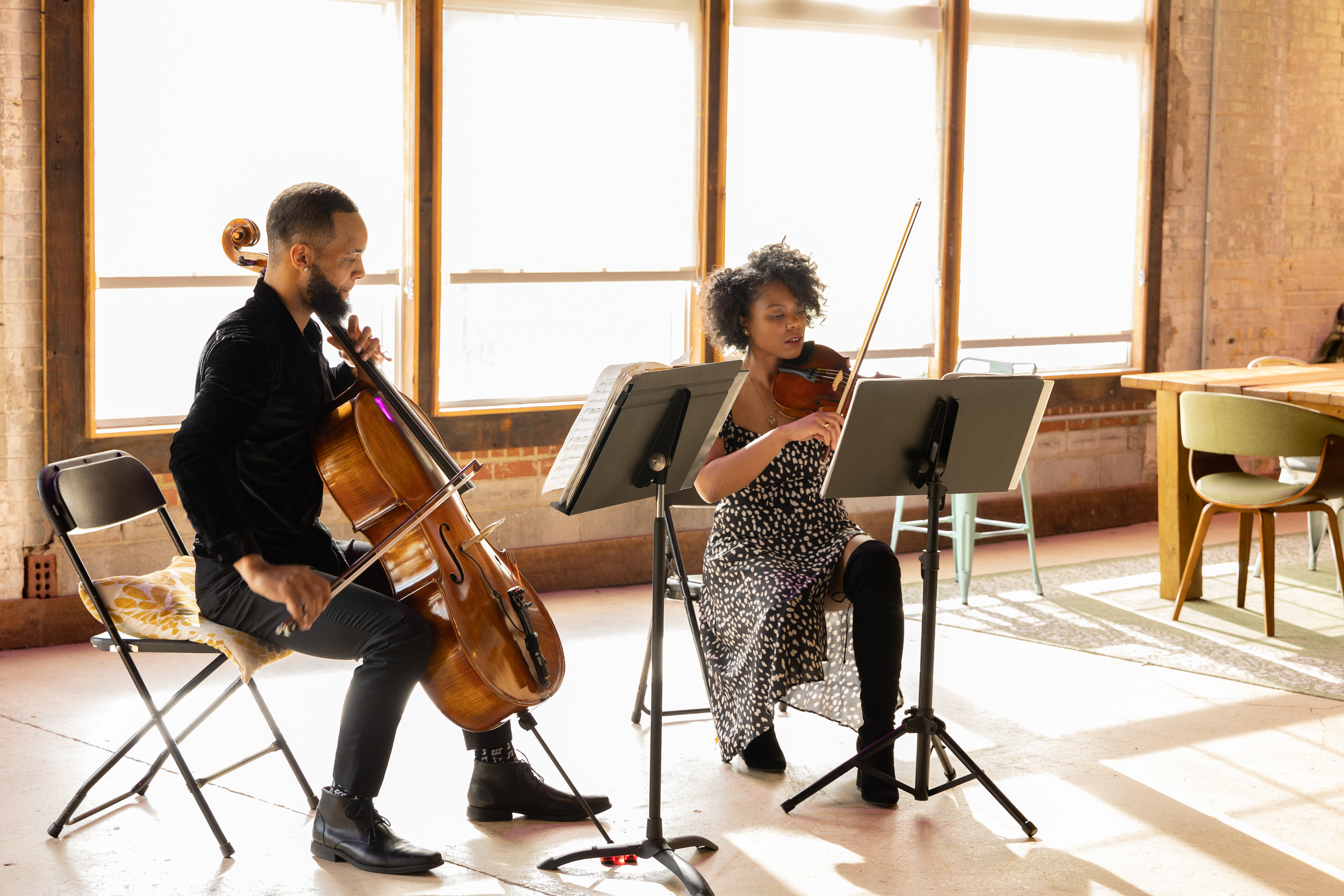Two violinists play in an open room