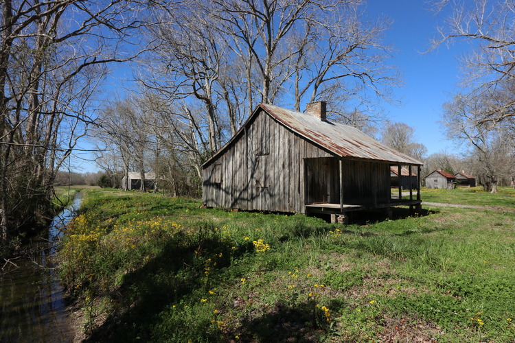 Wooden structure with metal roofing, centralized chimney, and front porch.