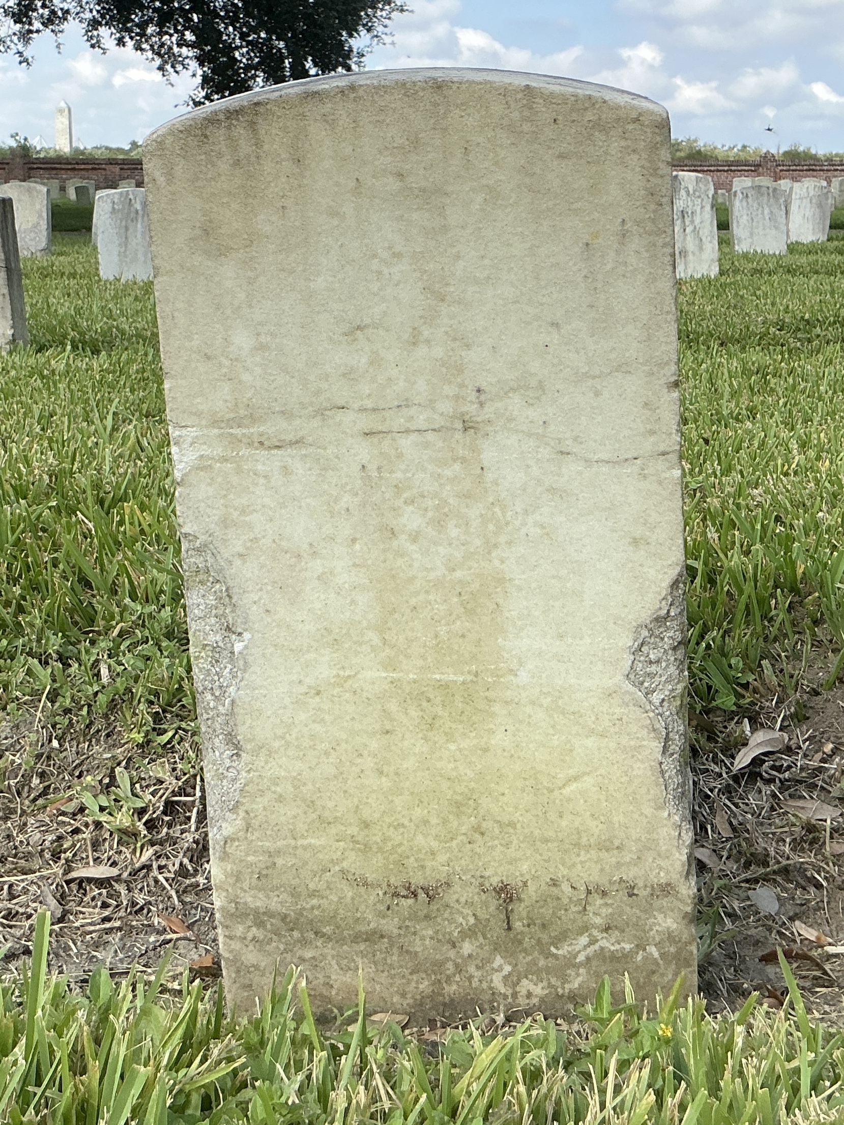 Back of historic upright marble headstone with recessed shield face.