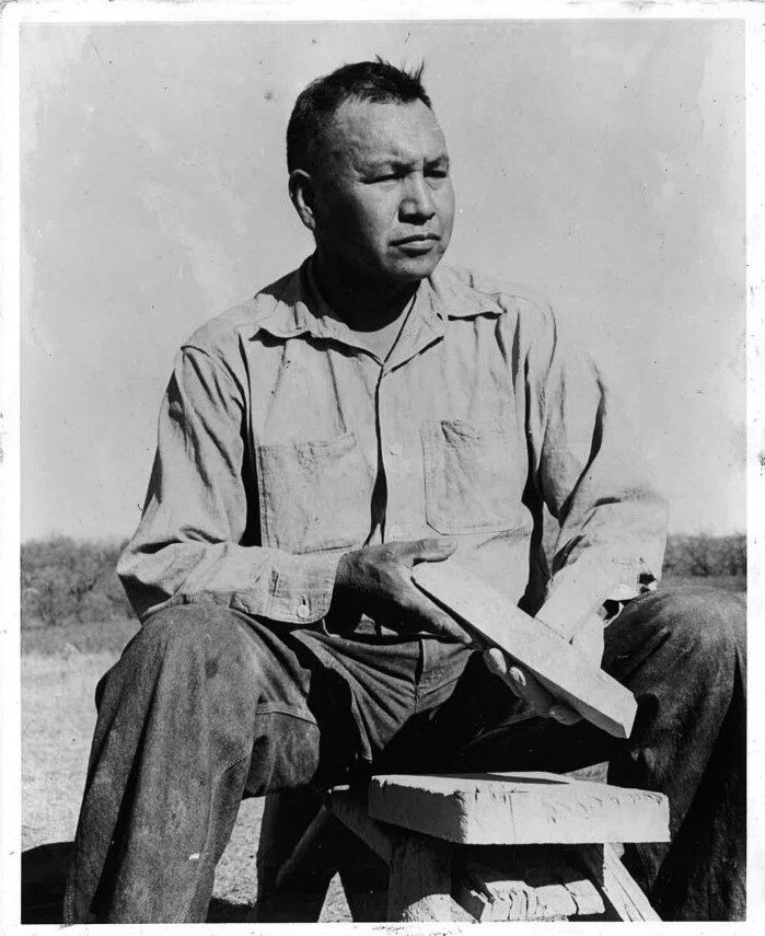 A man sitting outside holding a pipe blank