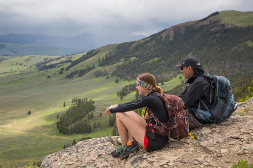 Man and woman sitting on high ridge looking out over the valley below