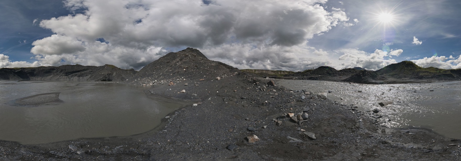 rocky, dirty landscape with pools of water and clumps of rocks over ice