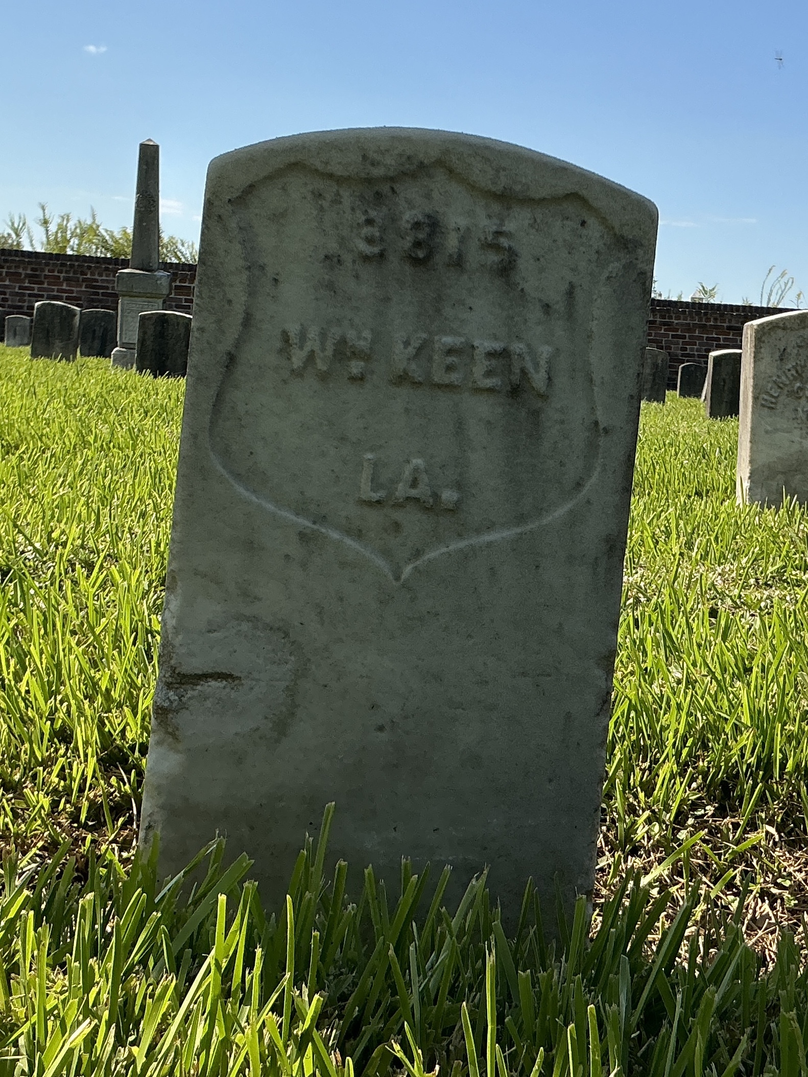 Front of historic upright marble headstone with recessed shield face.