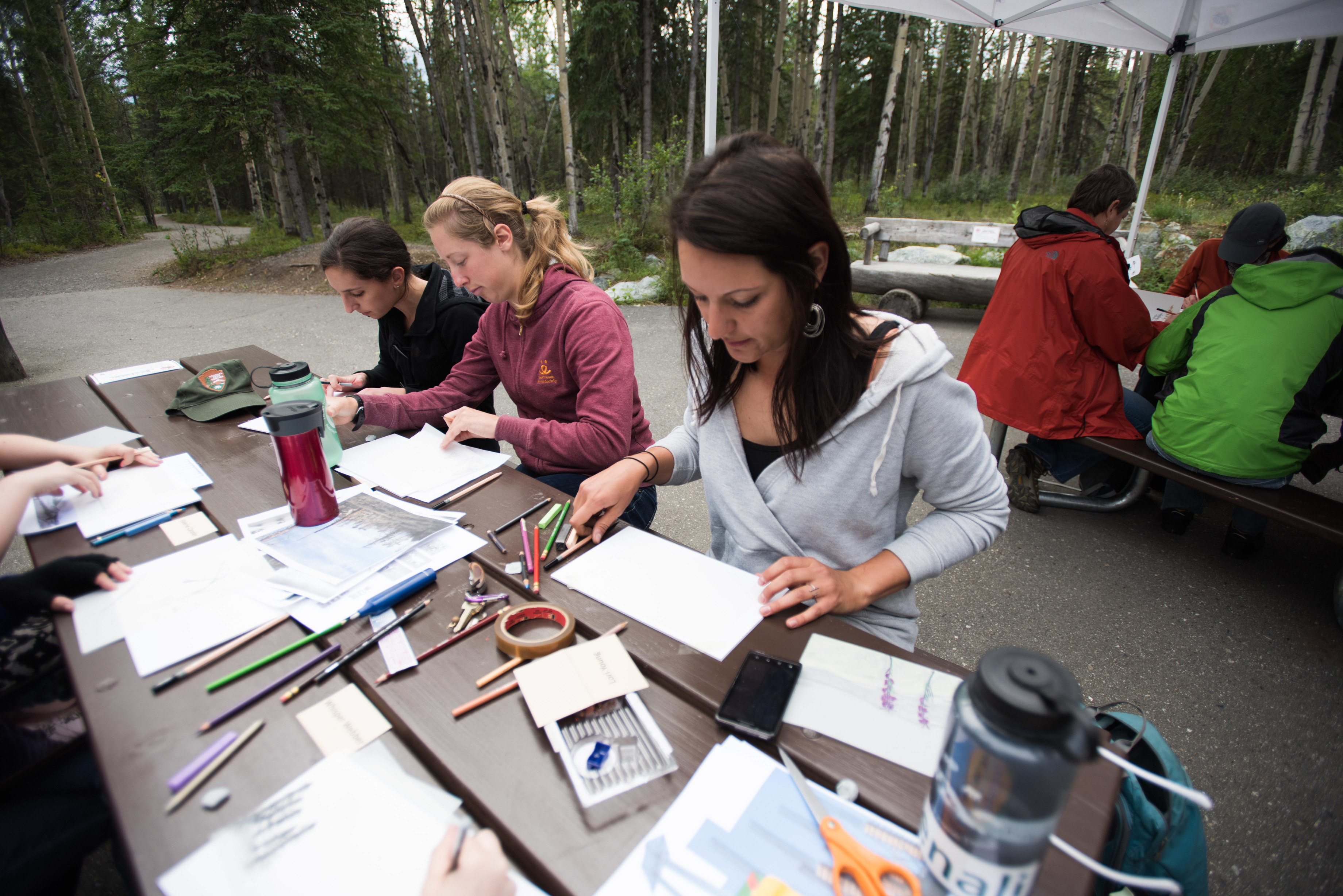 people at a picnic table with paper and color pencils