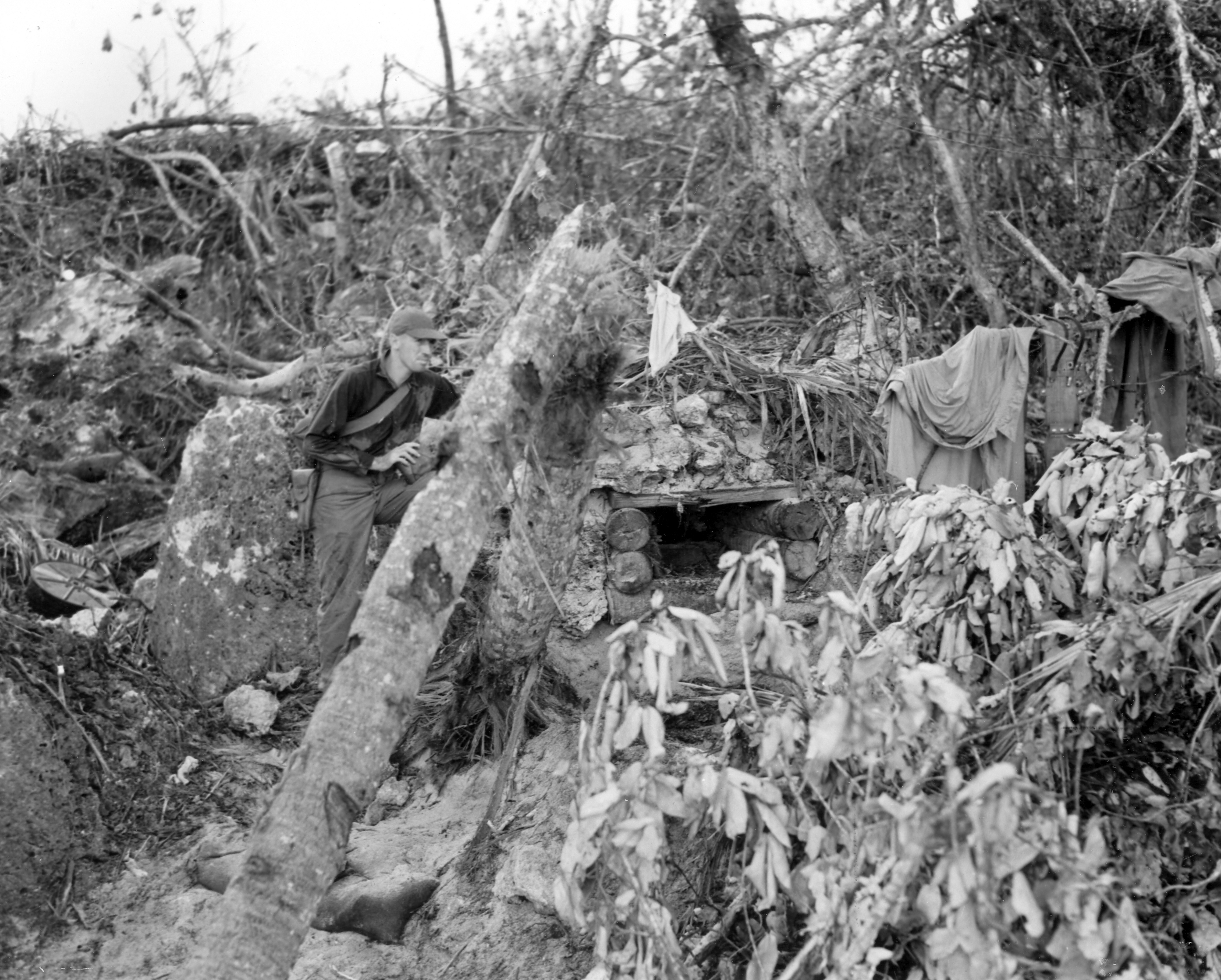 A soldier stands next to a well-concealed pillbox admits debris.