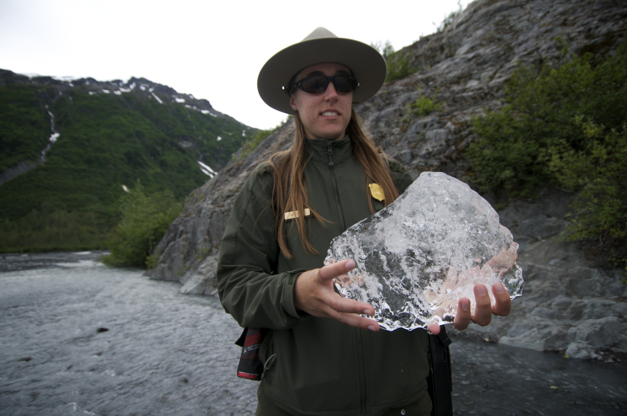 Interpretive Park Ranger Katie Peck holds up a piece of glacial ice taken from Exit Creek