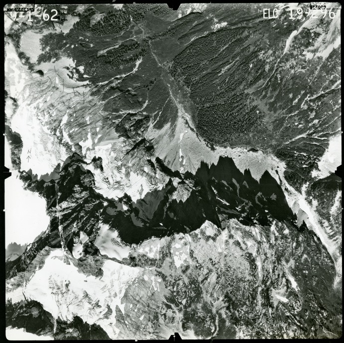 Black and white aerial photograph of glaciated mountain peaks and valleys.