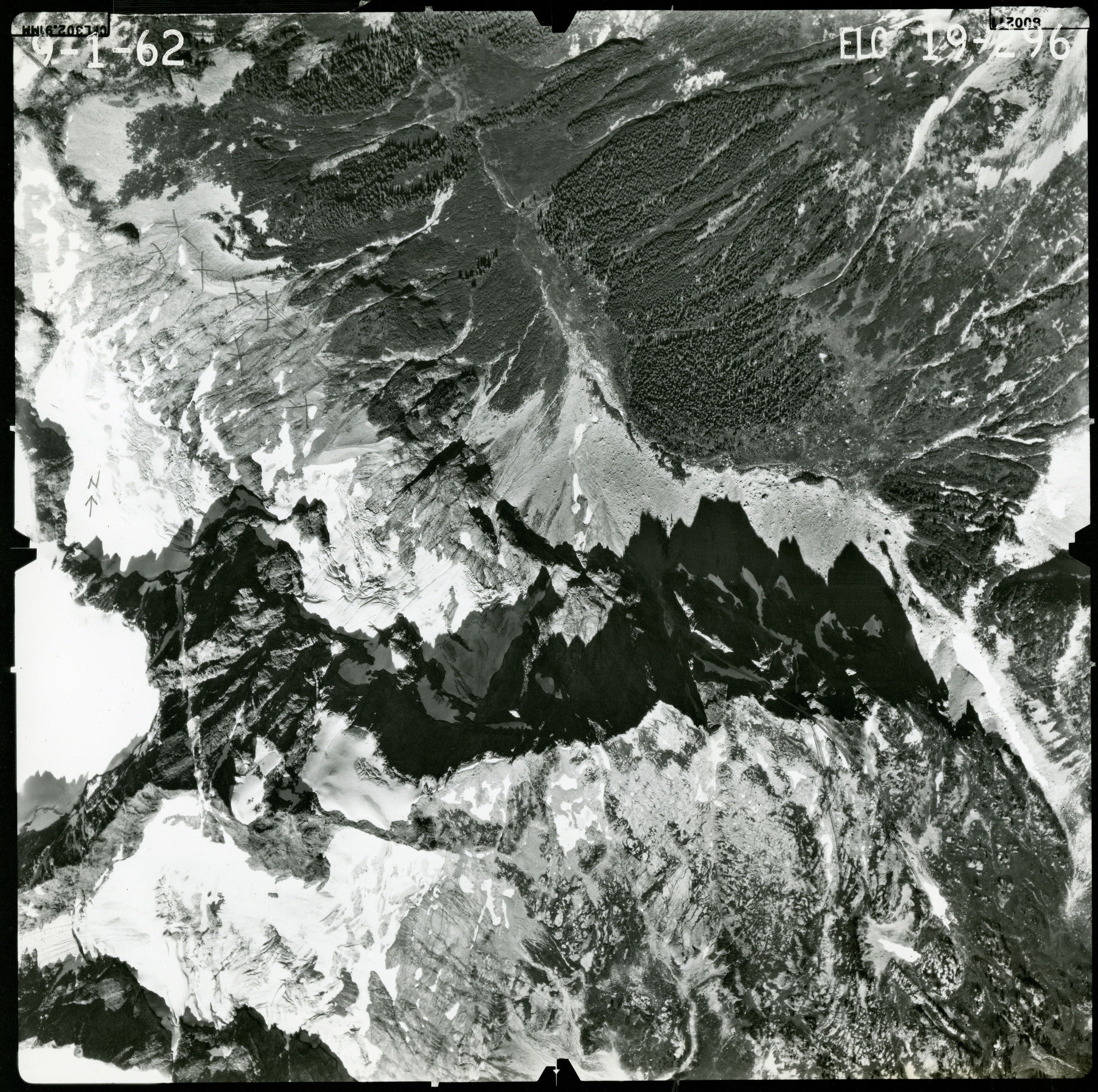 Black and white aerial photograph of glaciated mountain peaks and valleys.