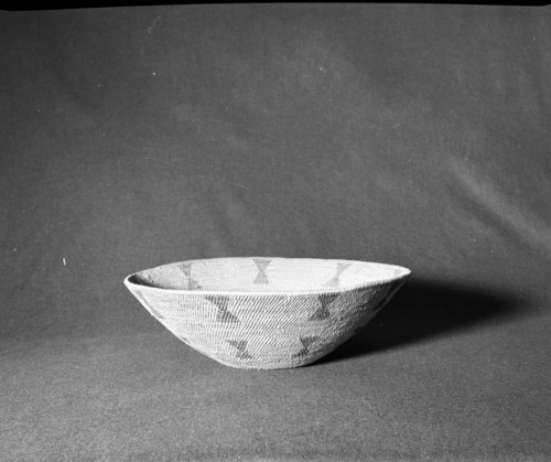 Marie Rozier Collection, Catalog No. 63. Object: Miwok basket. Dimensions: 16 x 5". Materials: Redbud, split bull pine. Technology: Leftward coil direction; fag ends trimmed on work face; moving ends trimmed on interior; fag ends also tucked back into hole were added; stitching on interior of start; flat bottom of basket is finished disc with workface on interior of basket; rods added to edge and workface changed to exterior for body of basket. Collection History: Alice Reade Collection. Photographed by Michael Dixon in December 1982. Catalogued by Craig Bates and Barbara Beroza. Yosemite Collections, National Park Service.