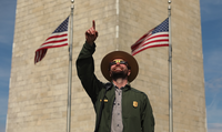 A Park Ranger points to a partial eclipse in front of the Washington Monument