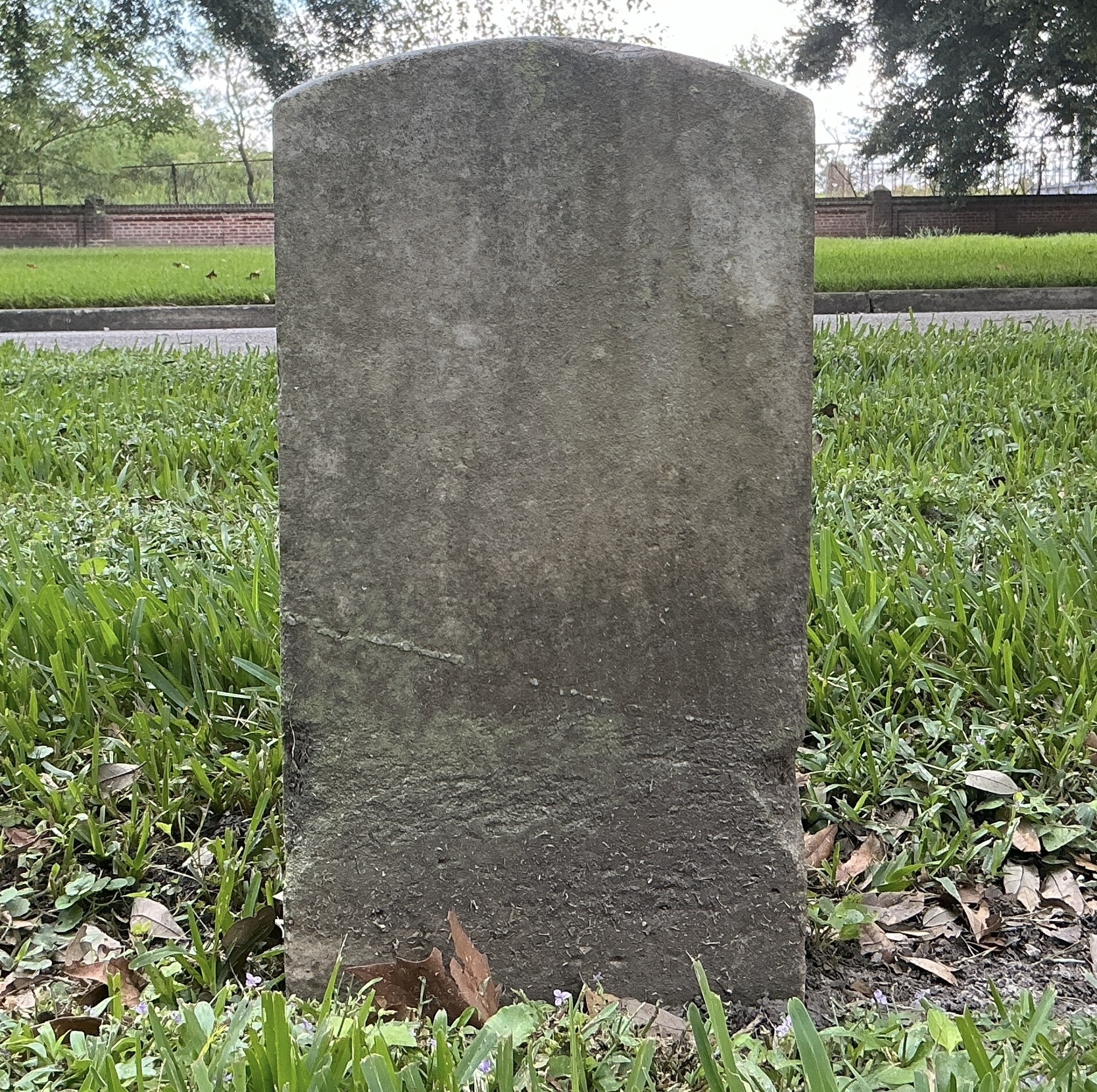 Back of historic upright marble headstone with recessed shield face.