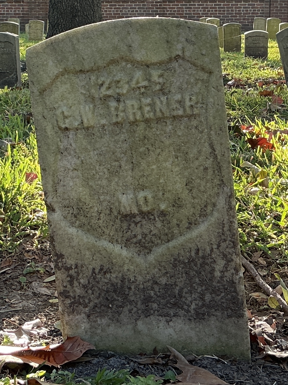 Front of historic upright marble headstone with recessed shield face.