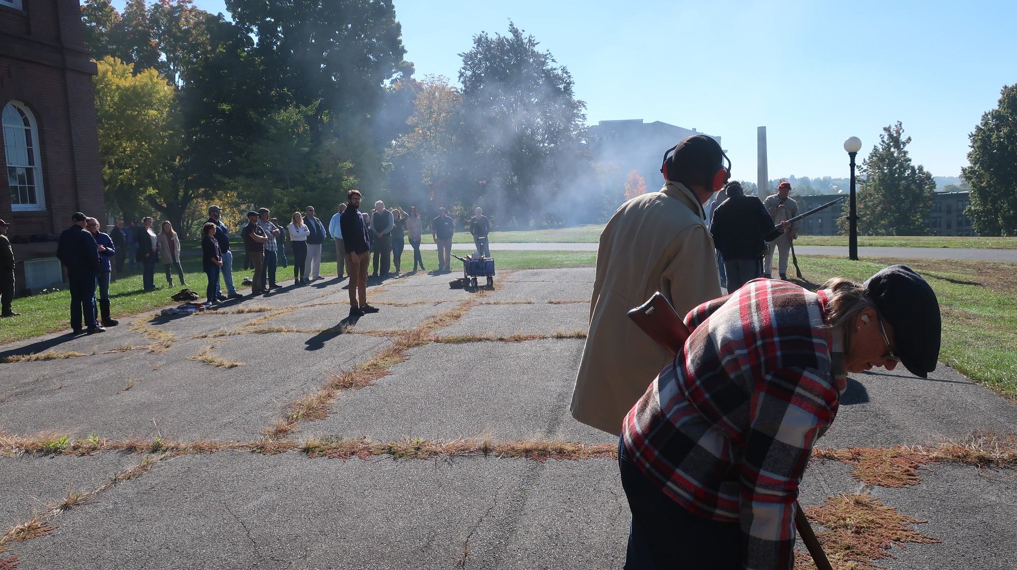 People operating firearms in a paved lot.