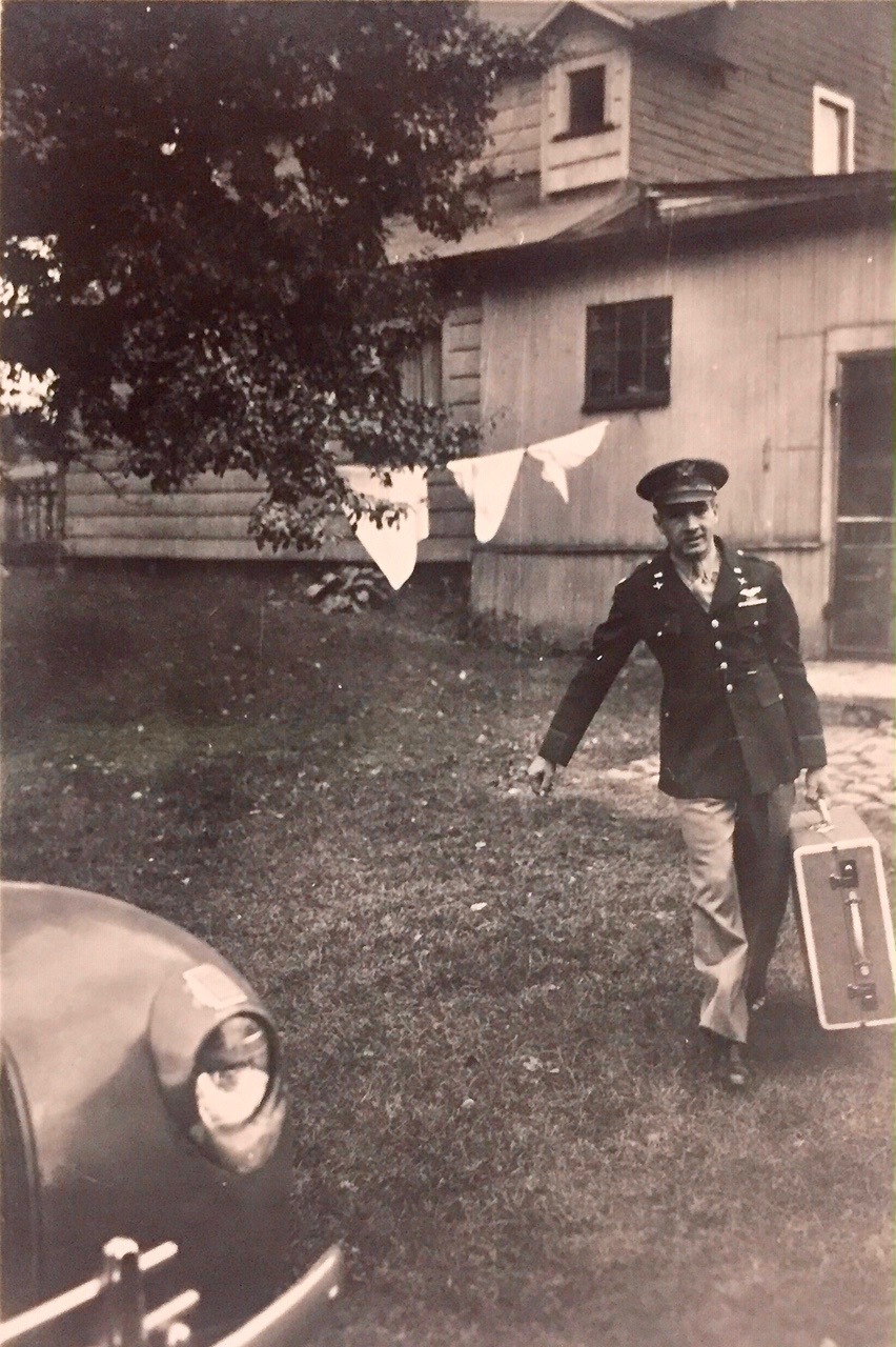 Man in uniform holding suitcase walking from house to a car. 
