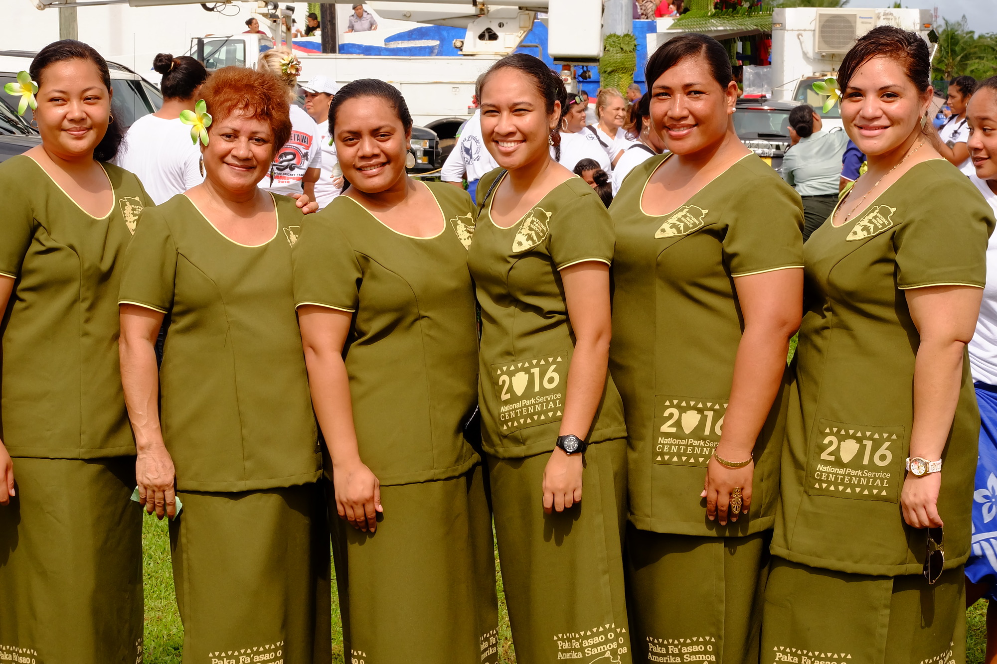 Six women employees from the National Park of American Samoa posing in green, two-piece traditional dresses called puletasi.