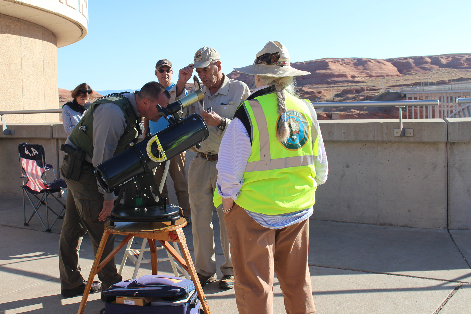 Park rangers stand around a solar scope on a homemade tripod. One looks through the eyepiece.