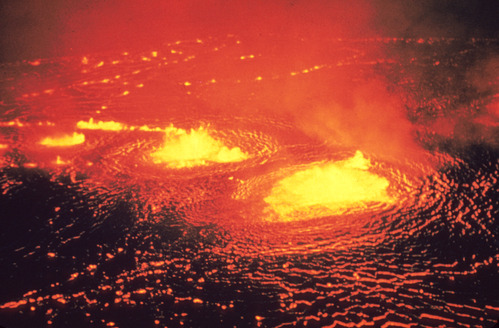 Glowing lava lake emitting gasses from multiple weak areas in its crust.