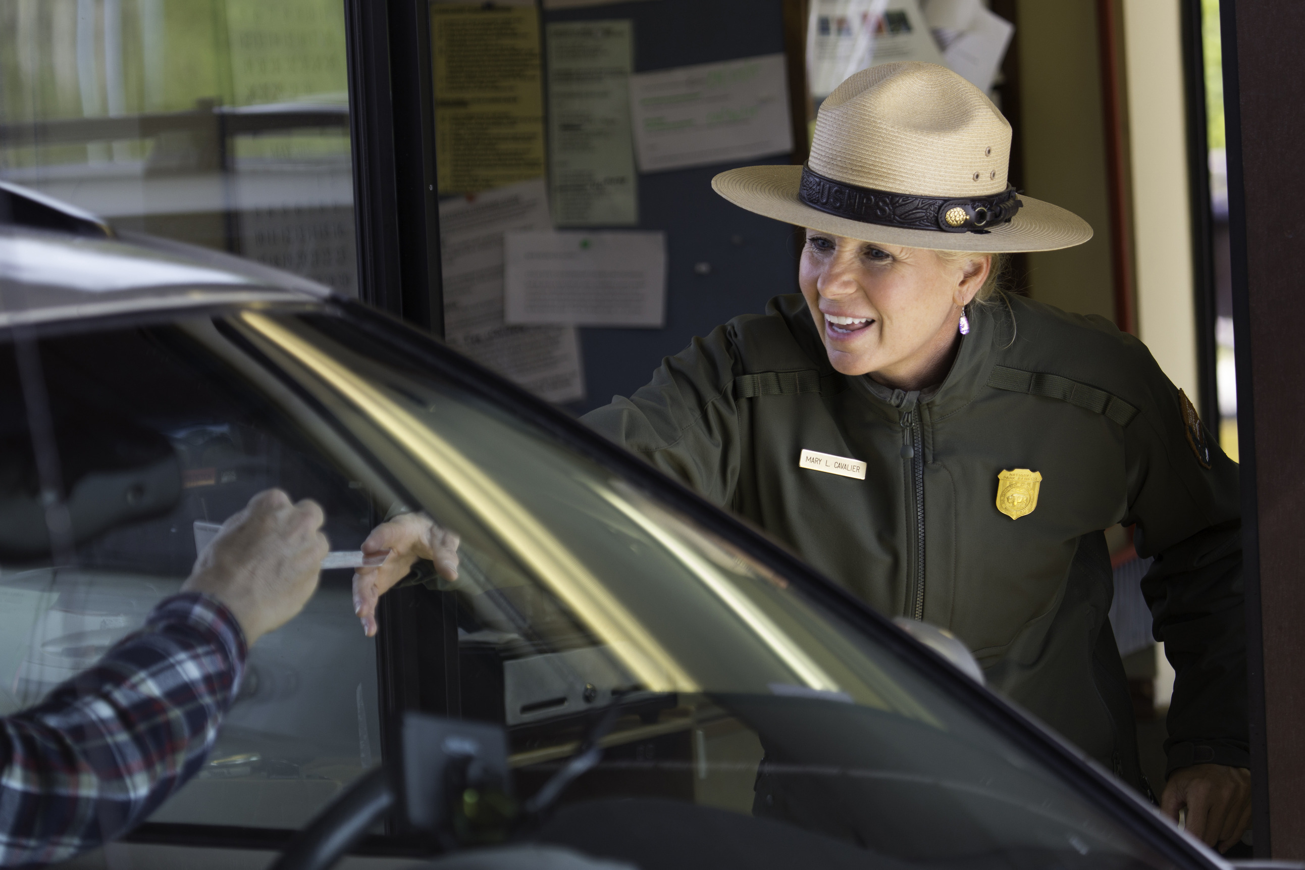 Ranger at entrance gate takes visitor's pass to look at.