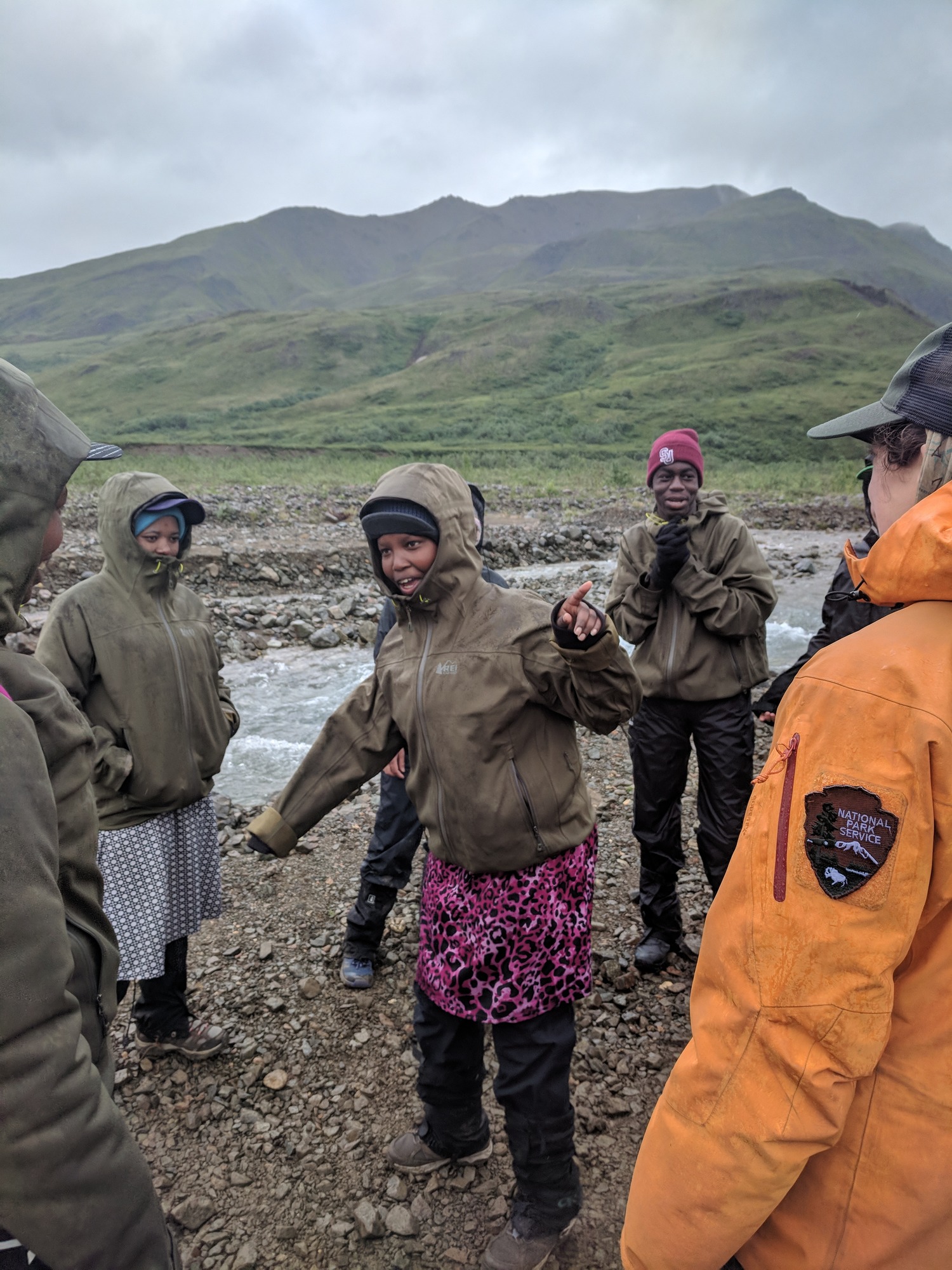 teens standing by a creek wearing hats and rain gear