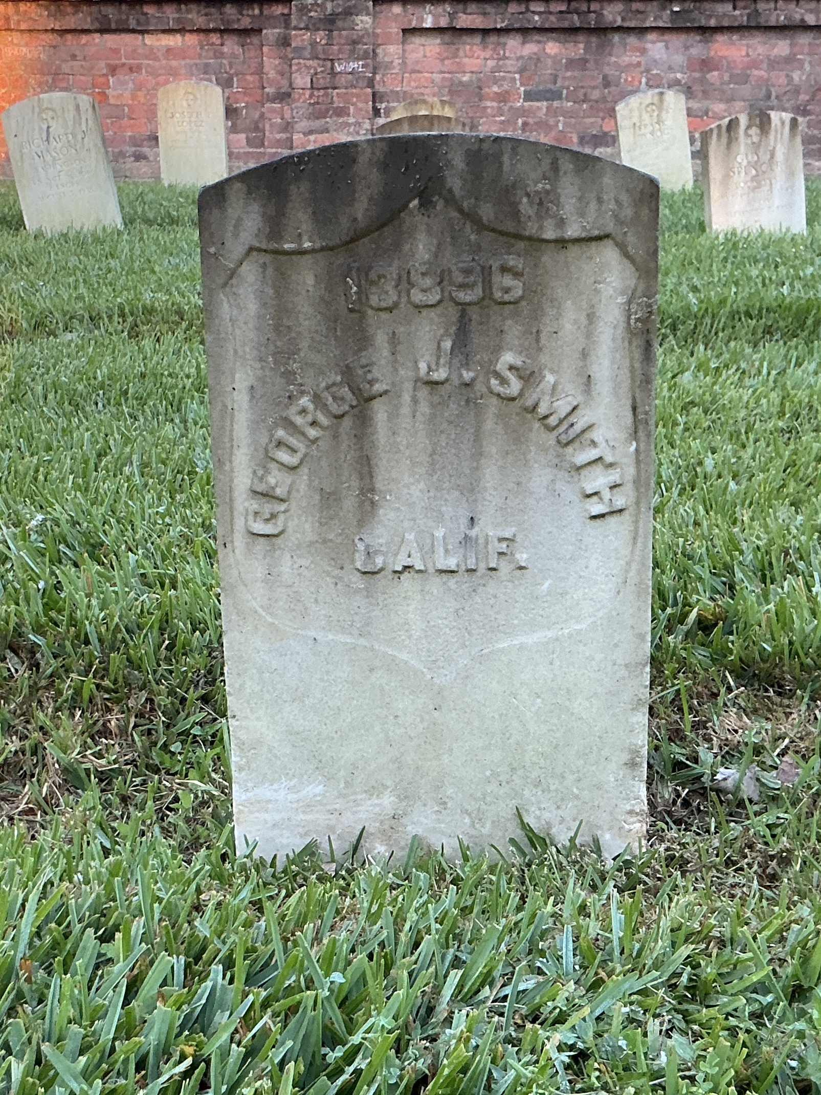 Front of historic upright marble headstone with recessed shield face.