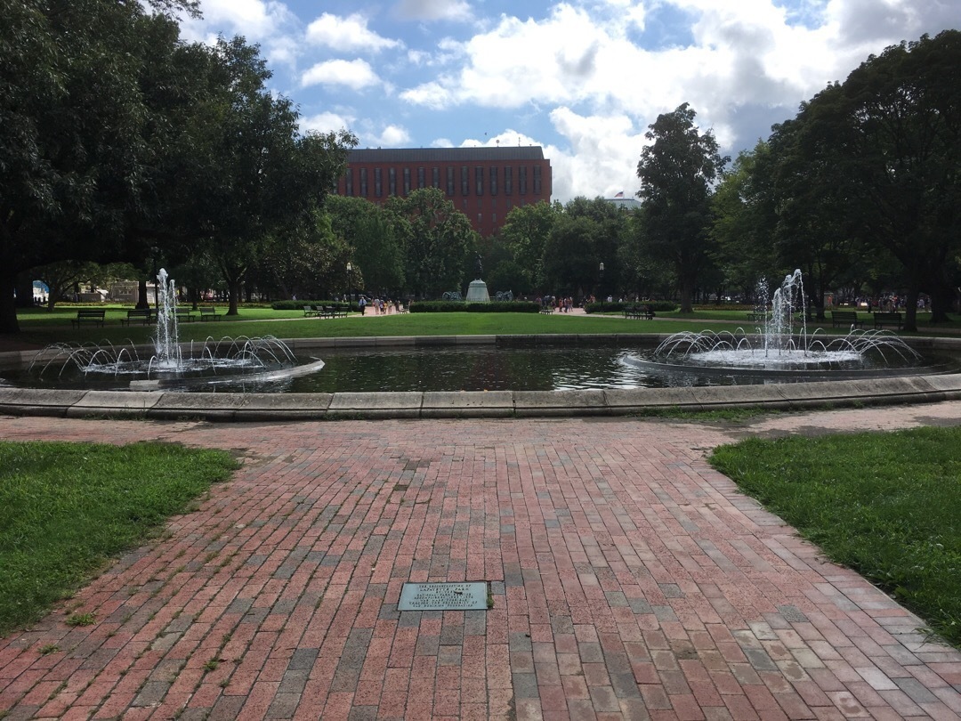 A red brick pathway leads to a water fountain
