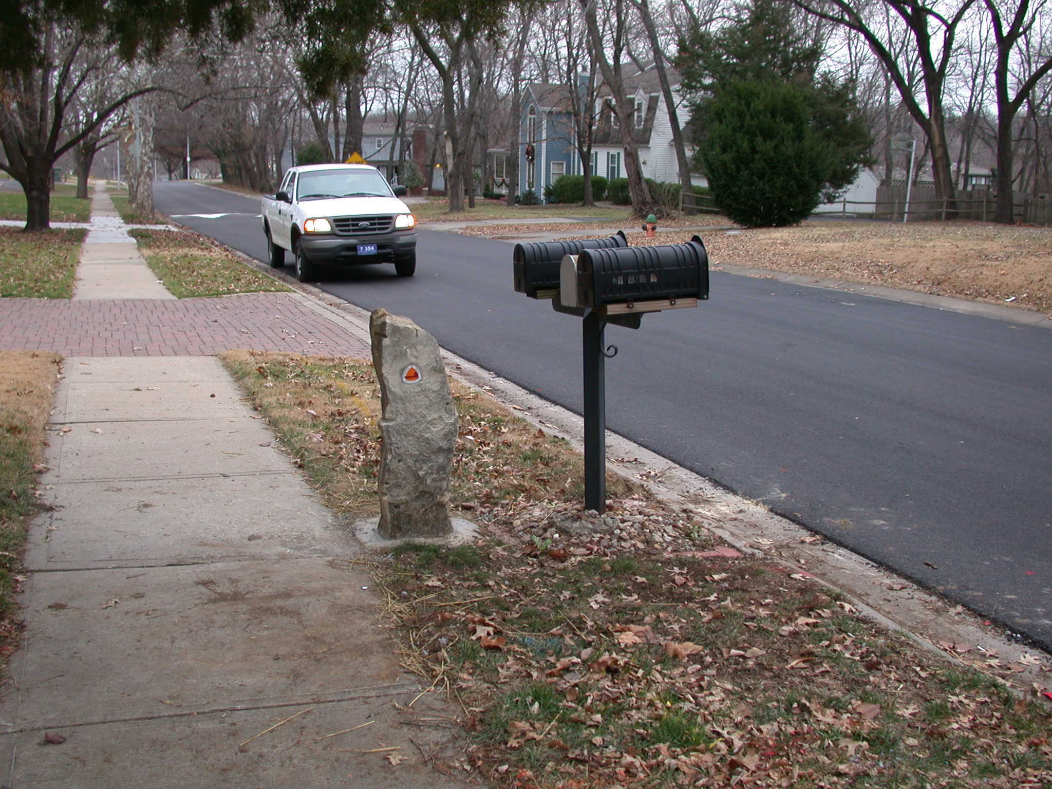 A pedestrian mailbox close to a road.