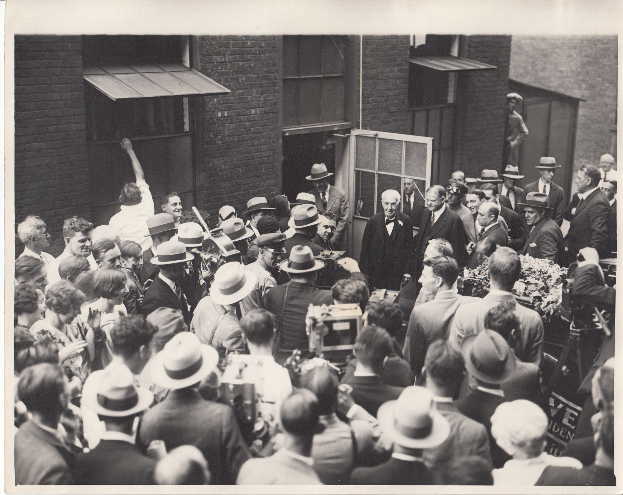 Herbert Hoover and Thomas Edison surrounded by photographers and reporters at the West Orange Laboratory exiting the Chemistry Lab on "Hoover Day."
