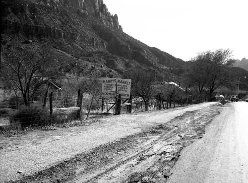 Roadside signs in Springdale. Obsolete signs of Hardy Jr. Supermarket. (tourist supplies, frozen foods, fresh meats, opposite Mormon church. Image also shows road construction.