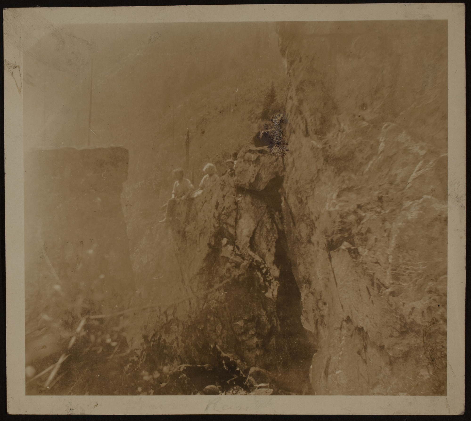 Four people sitting on an outcropping of rock along a cliff.
