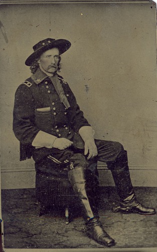 George Armstrong Custer in Military Dress Wearing Hat and Gloves Seated on an Ottoman