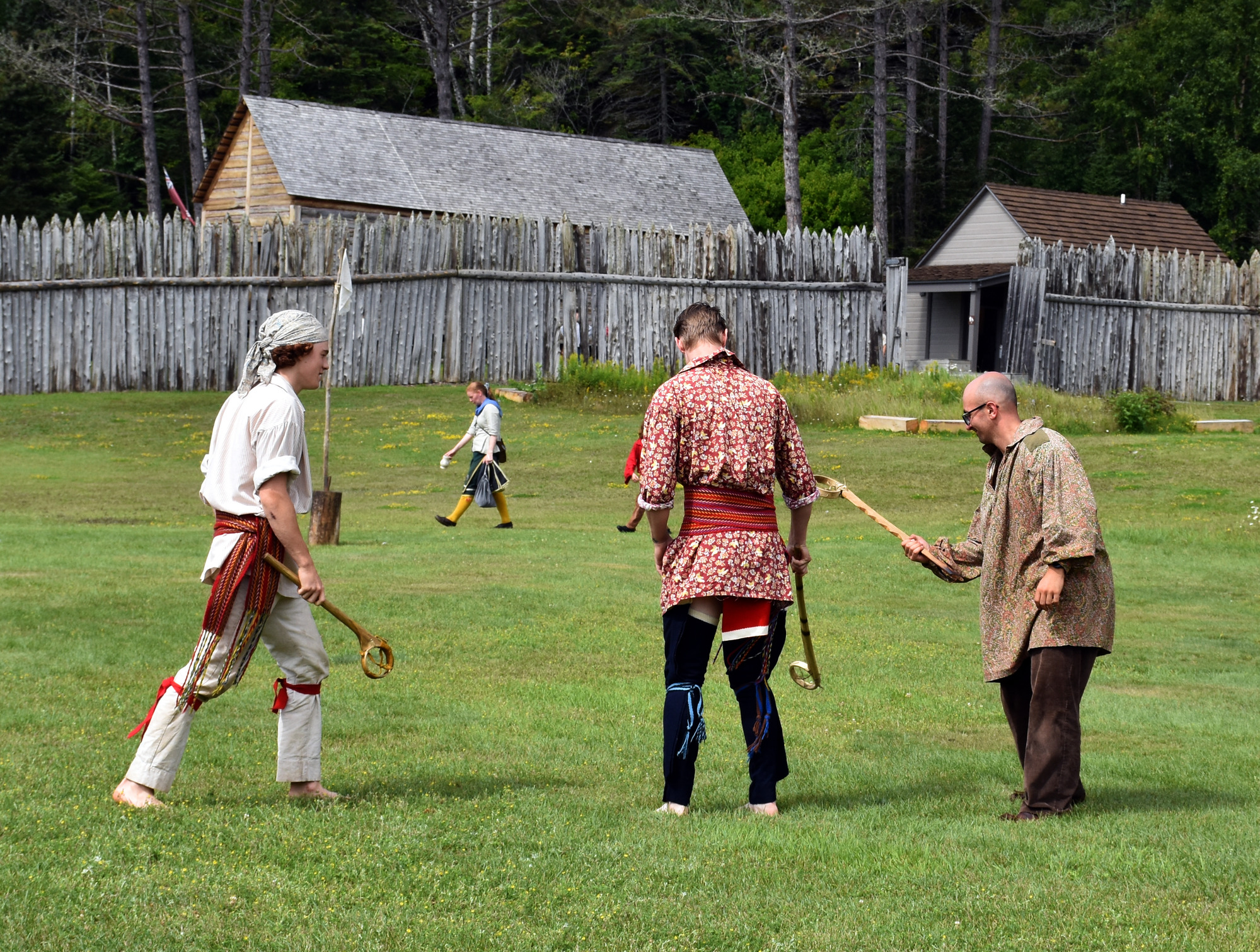 People in historic clothing holding lacrosse sticks.