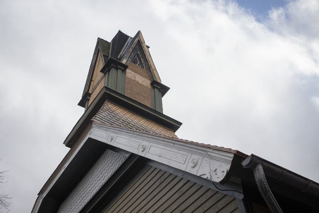 A view of the church steeple from below, with carved white molding along the edge of the roof.