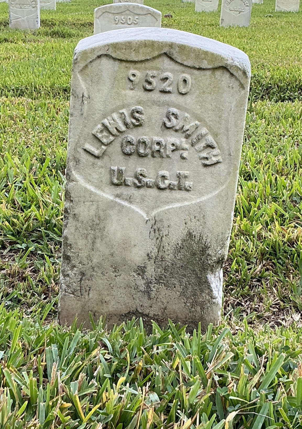 Front of historic upright marble headstone with recessed shield face.