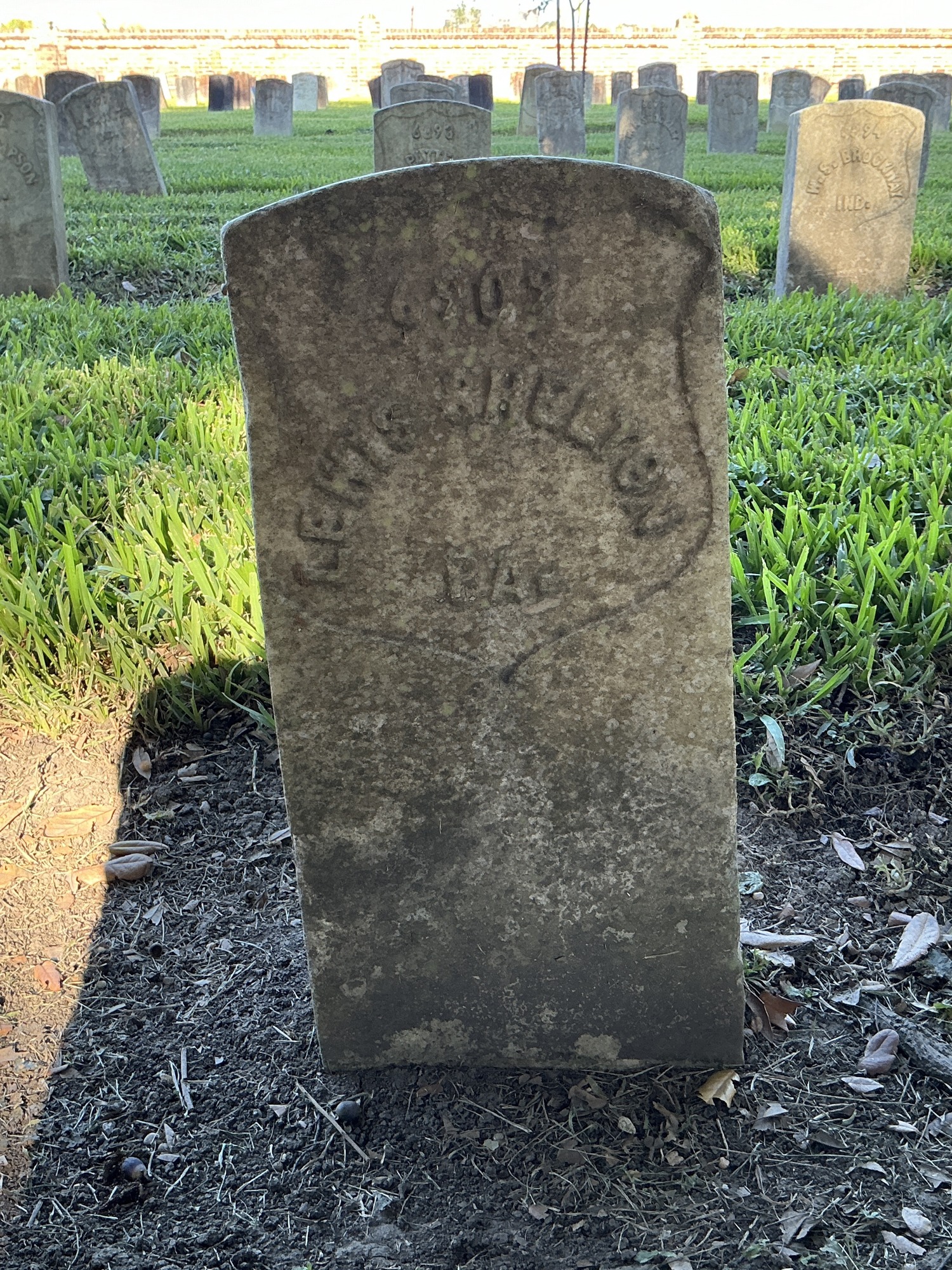 Front of historic upright marble headstone with recessed shield face.