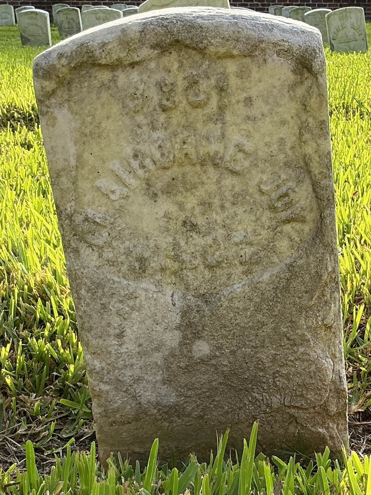 Front of historic upright marble headstone with recessed shield face.