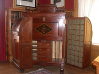 a large writing desk on wheels that has doors that open and there are 100 cubbie holes in it. 