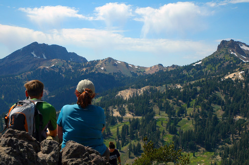 two people sitting and enjoying the view of mountains and trees