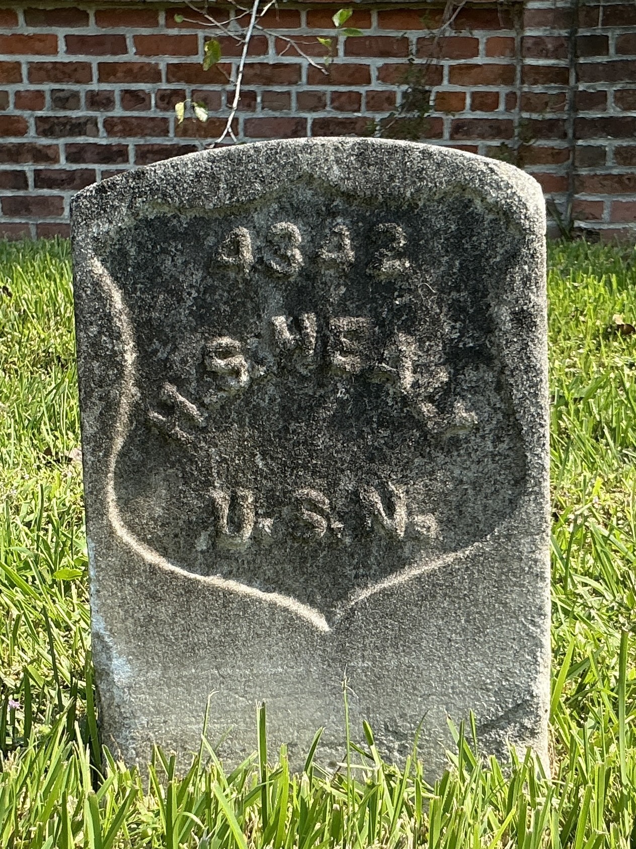 Front of historic upright marble headstone with recessed shield with recessed lettering face.