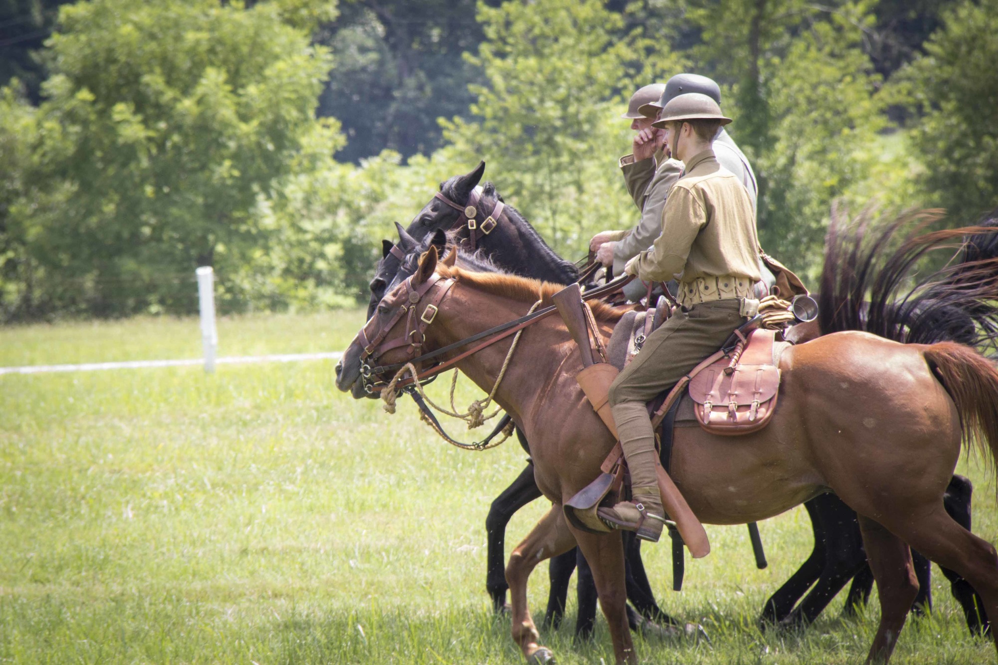 Three World War I living historians ride their horses during a cavalry demonstration.